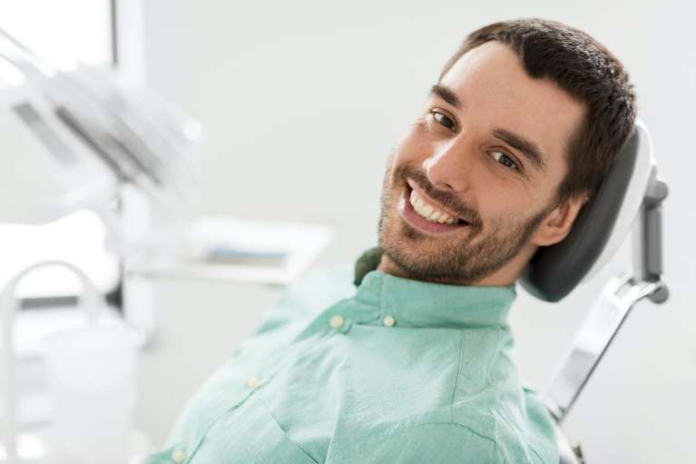 A smiling man getting a dental exam in Corona